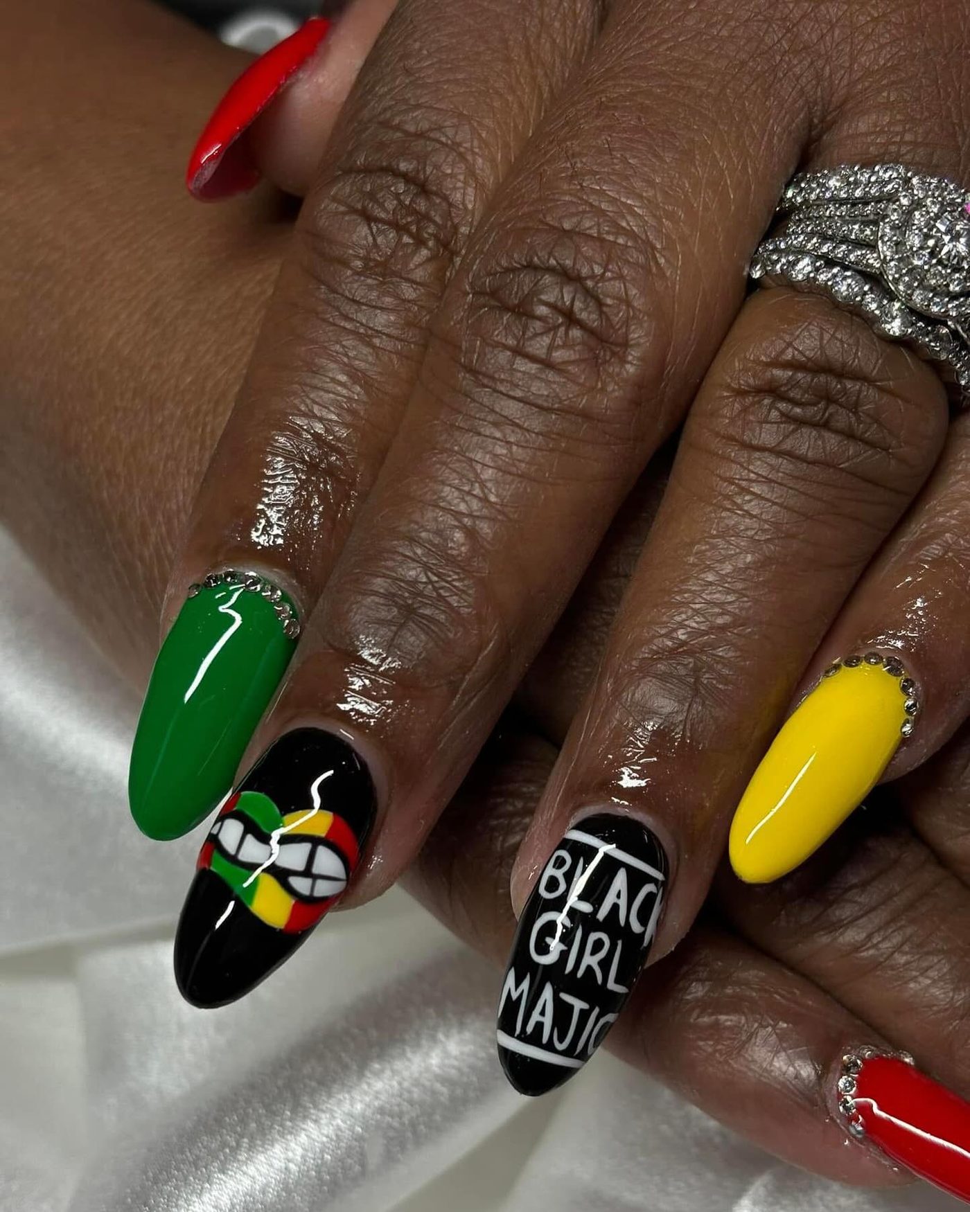 Bold hand-painted nail art in green, red, yellow, and black