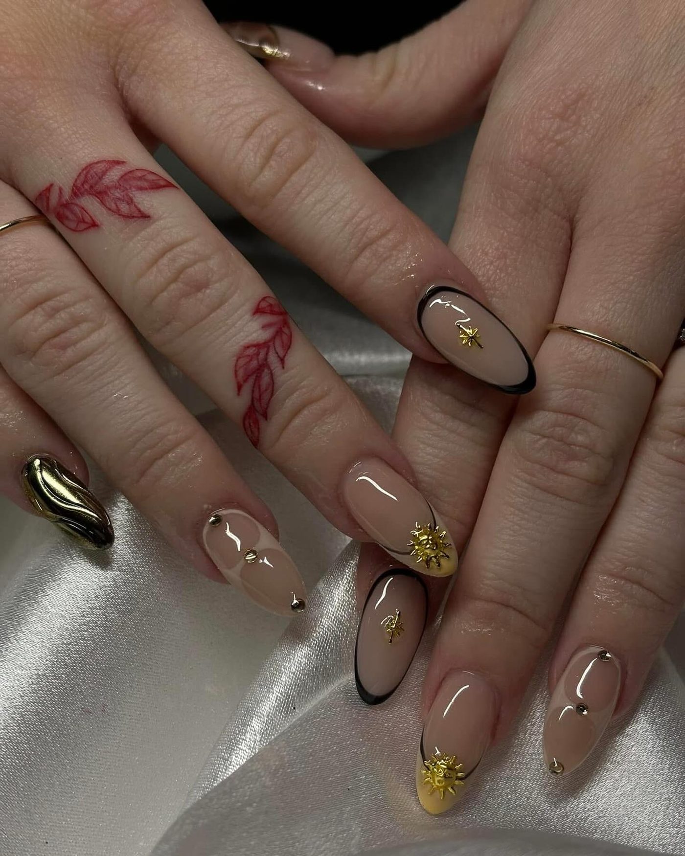 Nude nails with gold charms and black French tips